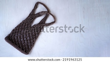 Brown string bag knitted in macrame technique from a knitted cord on a wooden background. Flat lay, top view. Zero waste and plastic free concept. A place for your text, advertising.