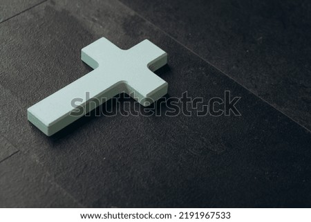 Christian cross on a textured black background. Religion concept. Blue cross