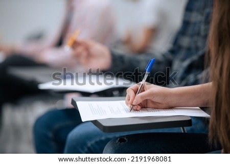 A close-up shot of a hand and a sheet of paper on which a student takes notes during a lecture at the university, without a face Royalty-Free Stock Photo #2191968081