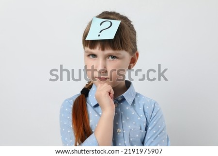 Pensive girl with question mark sticker on forehead against white background