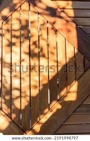 Looking down on a wooden Patio table top with shadows and sunlight