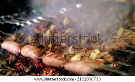 Grilled kebab cooking on metal skewer closeup. Roasted meat cooked at barbecue. BBQ fresh beef meat chop slices. Traditional eastern dish, shish kebab. Grill on charcoal and flame, picnic, street
