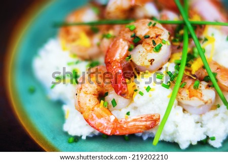 Shrimp and grits with cheese and chives on a rustic plate.  Royalty-Free Stock Photo #219202210