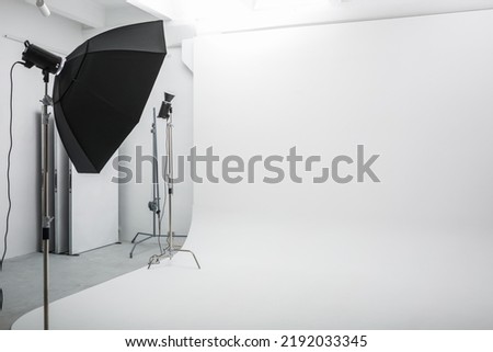 interior of bright space of photo studio with large white cyclorama with lighting equipment Royalty-Free Stock Photo #2192033345