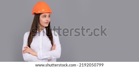 confident lady in safety hardhat and white shirt crossed hands looking aside, copy space, confidence. Woman isolated face portrait, banner with mock up copy space.