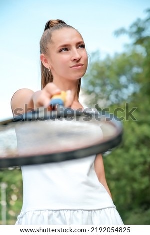 a girl in a white sports dress stands on a tennis court and holds a racket. portrait of a girl on the tennis court.