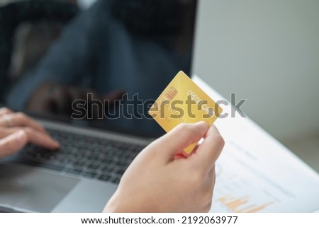 A woman uses a credit card to make online purchases on her laptop. credit card spending concept