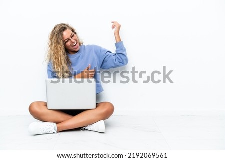 Girl with curly hair with a laptop sitting on the floor making guitar gesture