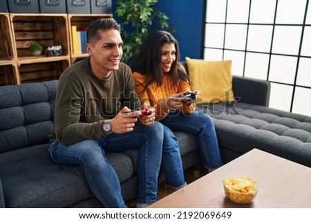 Man and woman couple playing video game at home Royalty-Free Stock Photo #2192069649