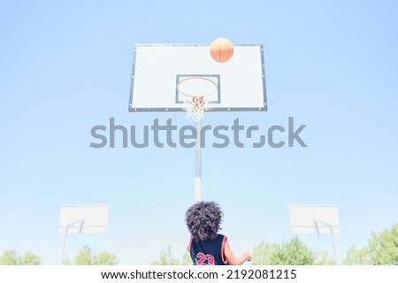 African-American boy waits for the ball to bounce off the backboard after a missed shoot in a basketball game on a court at a sports facility. Healthy life concept. Royalty-Free Stock Photo #2192081215