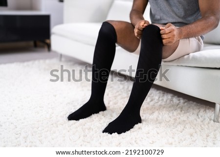 Man Putting On Medical Compression Stockings On Legs Royalty-Free Stock Photo #2192100729