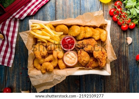 assorted beer snacks, chicken nuggets, french fries, shrimps temputa and chicken wings top view Royalty-Free Stock Photo #2192109277