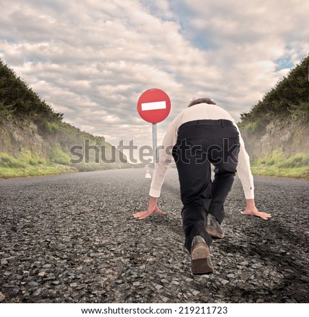 businessman on a road ready to run with No Entry Traffic Road Sign in front