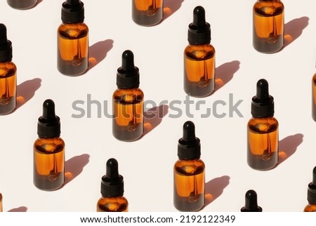 Pattern of Transparent amber green glass dropper bottles with liquid inside on beige background in the sunlight. Pipette with fluid hyaluronic acid, serum, retinol. Cosmetics, healthcare, beauty 