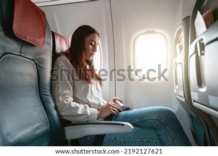 Woman passenger fastening seatbelt sitting in airplane before flight Royalty-Free Stock Photo #2192127621