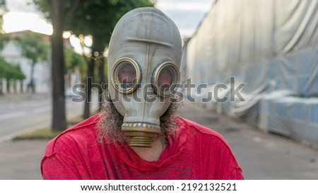 Strange man in a gas mask standing on the street in an empty city. Man wearing anti-pollution, anti-smog and viruses face mask. Man in a chemical gas mask posing on the street. Royalty-Free Stock Photo #2192132521
