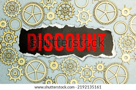 Wooden cubes with the word DISCOUNT stand on a wooden background between a magnifying glass and a pen