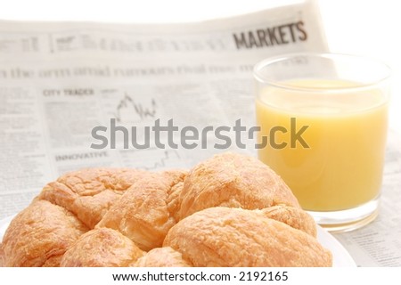Glass of refreshing orange fruit juice and croissant over business paper with graphs and word 'market', macro