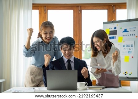 Group of Asian business people standing smiling raised their hands up happy standing at table in the office. Group of successful Asian business teams discusses collaboration and analyzes reports work. Royalty-Free Stock Photo #2192165437