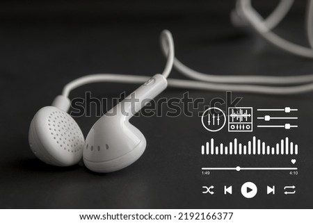 white headphones on a black background There are play button symbols, song skip buttons, square and circular equalizer strip symbols. The top is an orchestral shape, suitable for music media. Royalty-Free Stock Photo #2192166377