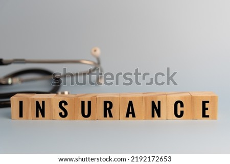 wood cube block insurance medical stethoscope on table concept.