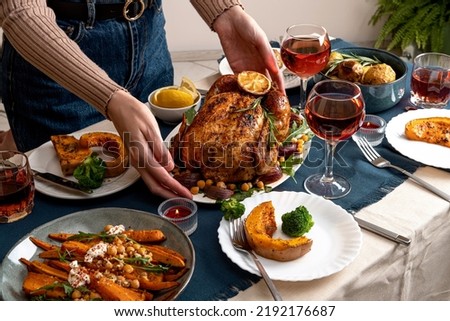 People celebrating Thanksgiving Day. 
Thanksgiving party table setting. Traditional holiday stuffed baked chicken dinner and vegetable. Family party or gathering.
