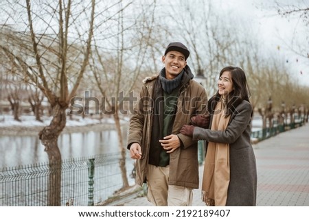 happy couple enjoying their time together walking near a river in winter