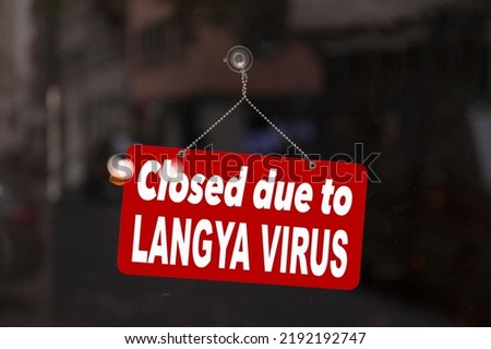 Close-up on a red sign in the window of a shop displaying the message in English - Closed due to Langya virus -.