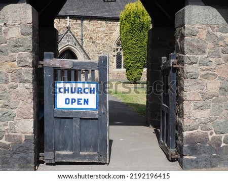 church open sign fixed to a wooden gate with church and churchyard in the background.