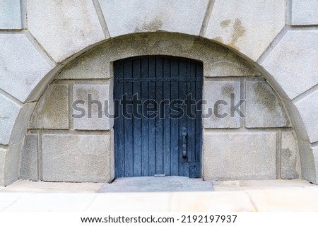 Wooden door of black color in a stone arch