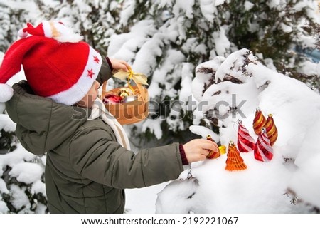 Child decorating Christmas tree in the forest. . Family with kids celebrate winter holidays. Kids decorate Christtmas tree in good weather