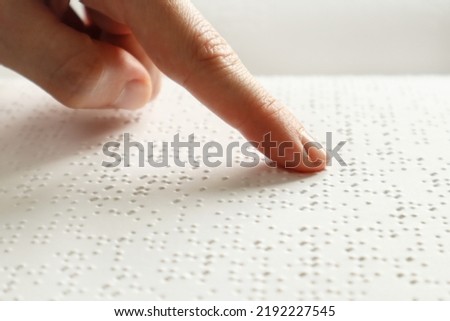 A blind man reads a Braille book with his hands