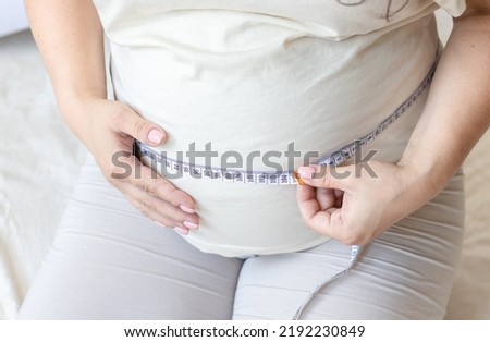 pregnant woman sitting on bed measuring big belly female advanced pregnancy last trimester of pregnancy.future mother before childbirth prenatal.exited female using measure tale.fetus in uterus baby 