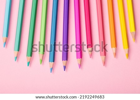 Beautiful wooden multi-colored colors pencils close-up on a pink paper background, top view. The concept of back to school, an example screensaver for a drawing studio for children, stationery store.
