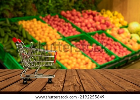 Supermarket table background. A counter with blurred vegetables and empty wooden table. Grocery, food, products, retail concept. 
