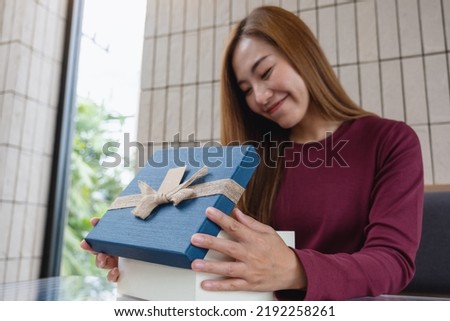 Portrait image of a young woman receiving and opening a red present box