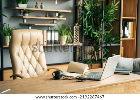 Modern office of general manager, businessman, ceo. Stylish wooden table, leather chair, interior. Workplace, workspace of accountant, financial director. Shelves with documents. Home library. Royalty-Free Stock Photo #2192267467