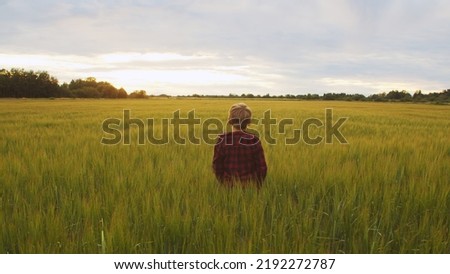 Boy in front of a sunset agricultural landscape. Kid in a countryside field. Childhood, country life, farming and country lifestyle. Royalty-Free Stock Photo #2192272787