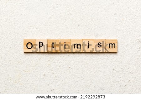 Optimism word written on wood block. Optimism text on cement table for your desing, concept.