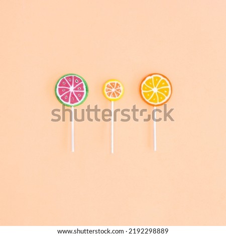 Three fruity lollipops on beige background. Flat lay