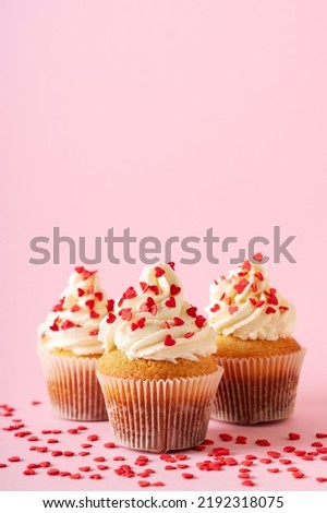 Vanilla cupcakes close up on with heart shape confectionery sprinkles on pink background, copy space, valentine day, mothers day concept, vertical