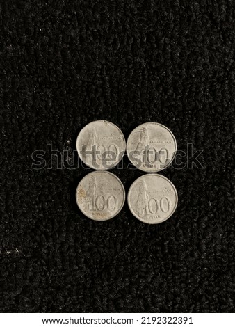 One hundred rupiah Indonesian coin with a picture of a parrot isolated on a dark background
