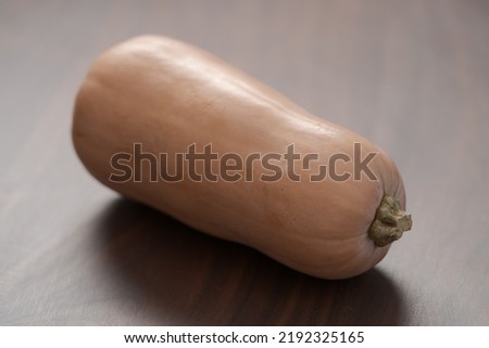 Whole butternut squah on walnut wood table, shallow focus Royalty-Free Stock Photo #2192325165