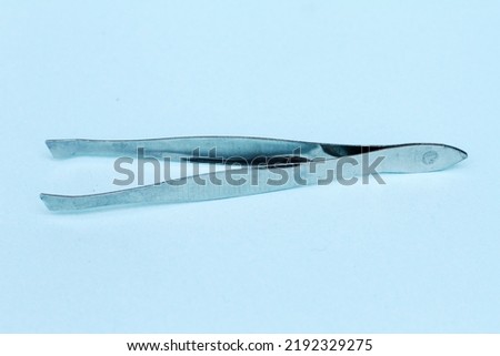 Stainless steel tweezers on a blue background, very cool for cosmetic tool sellers
