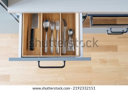 keeping silverware in box from wood or opened drawer with spoons, forks, knife in modern kitchen cupboard Royalty-Free Stock Photo #2192332151