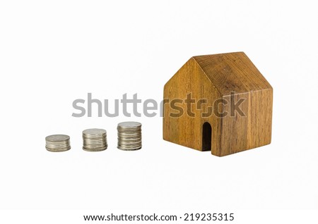 wooden toy house with coins concept of dearness of habitation on white background