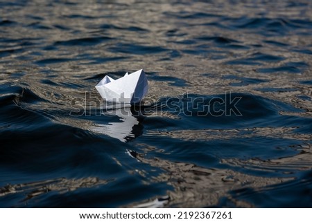 A lonely paper boat on the waves. Background picture. Space for printing text.