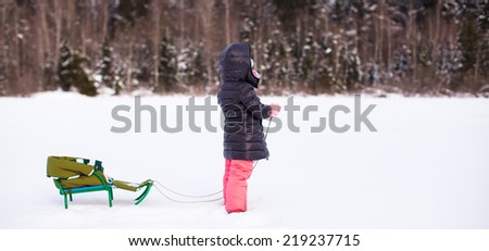 Little cute girl go sledding on a warm winter day