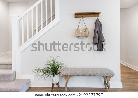 Simple foyer with staircase bench hanging purse and jacket Royalty-Free Stock Photo #2192377797