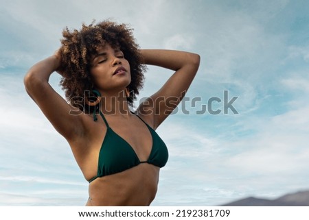 Portrait of beautiful afro girl in bikini with beach background.